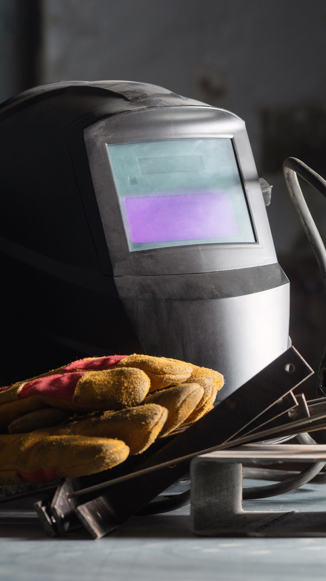 Welding helmet on the metal workbench background.